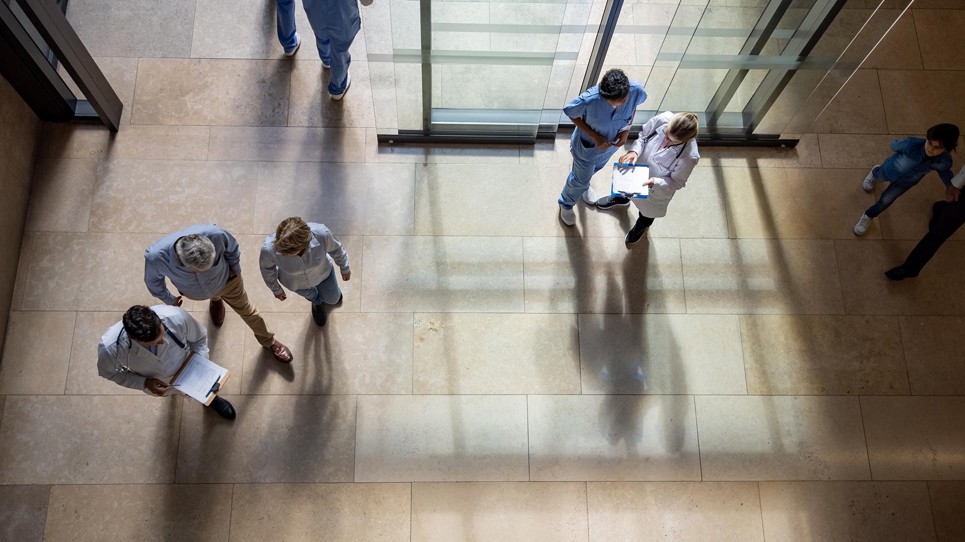 Doctors and nursing conversing in a sunny hospital lobby.