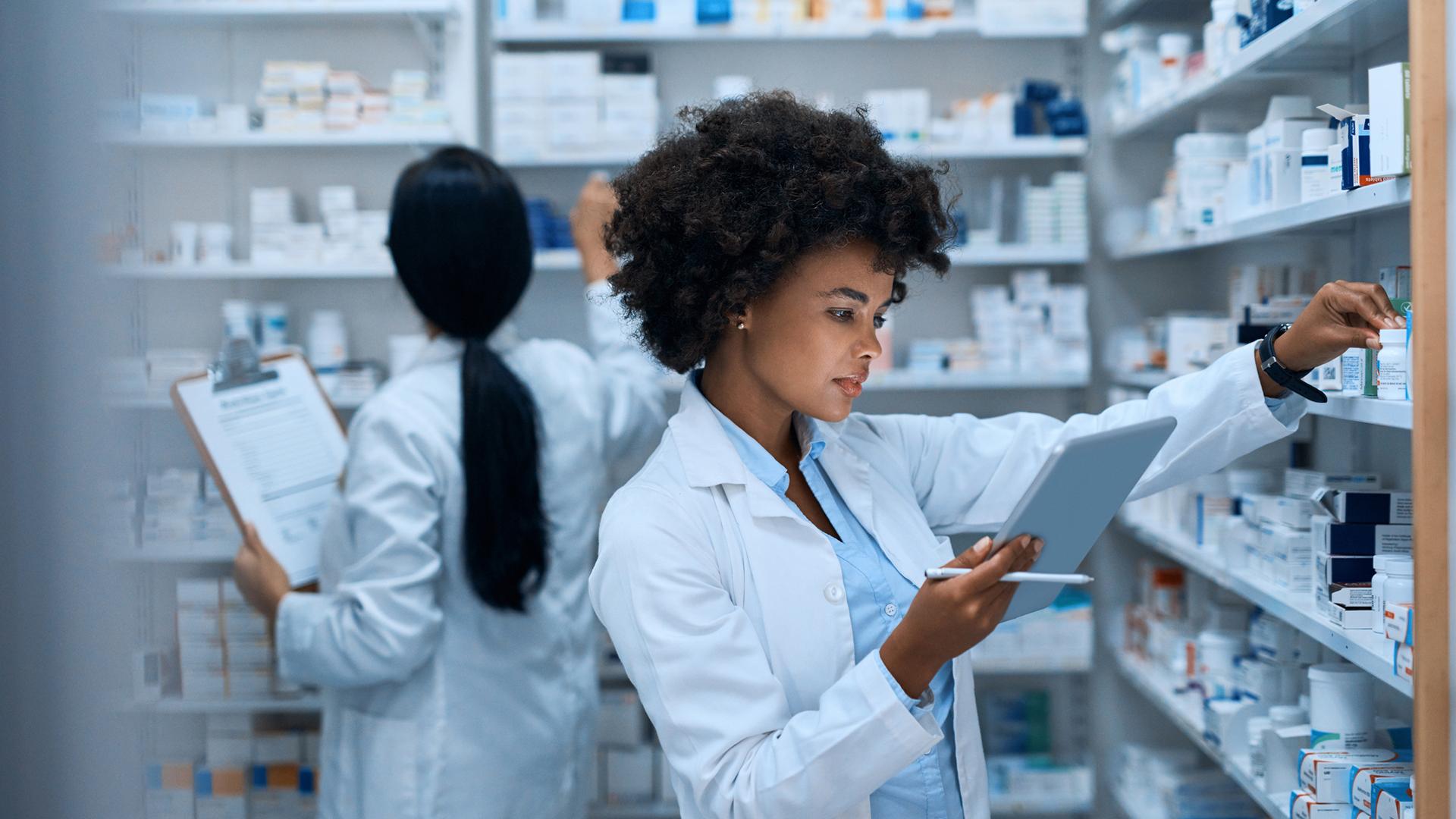 Two pharmacists checking prescriptions in inventory