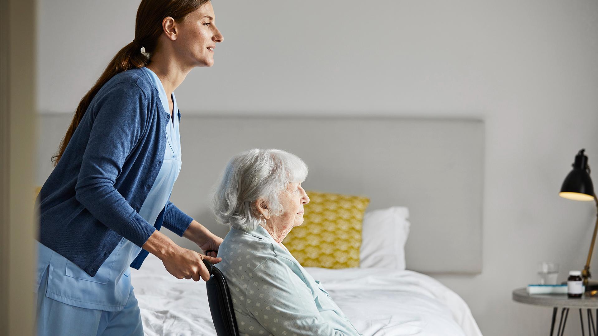 Nurse with elderly woman on wheelchair at home