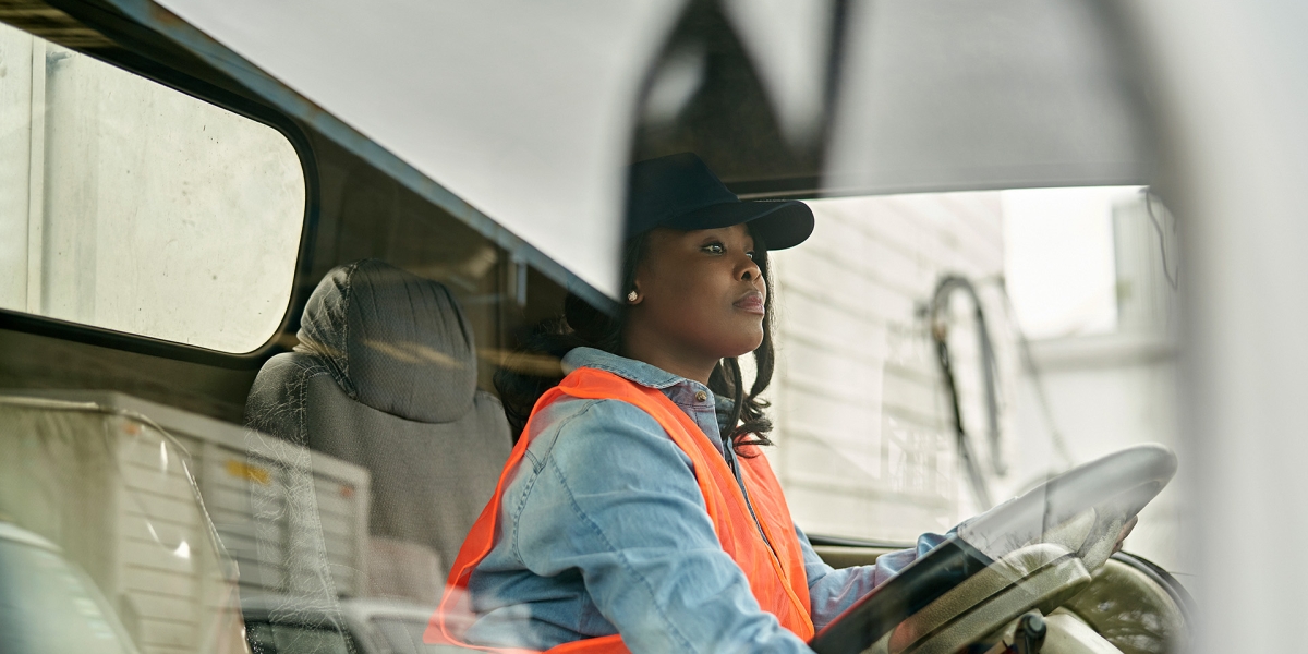 A woman sitting in the drivers seat of a semi-truck.
